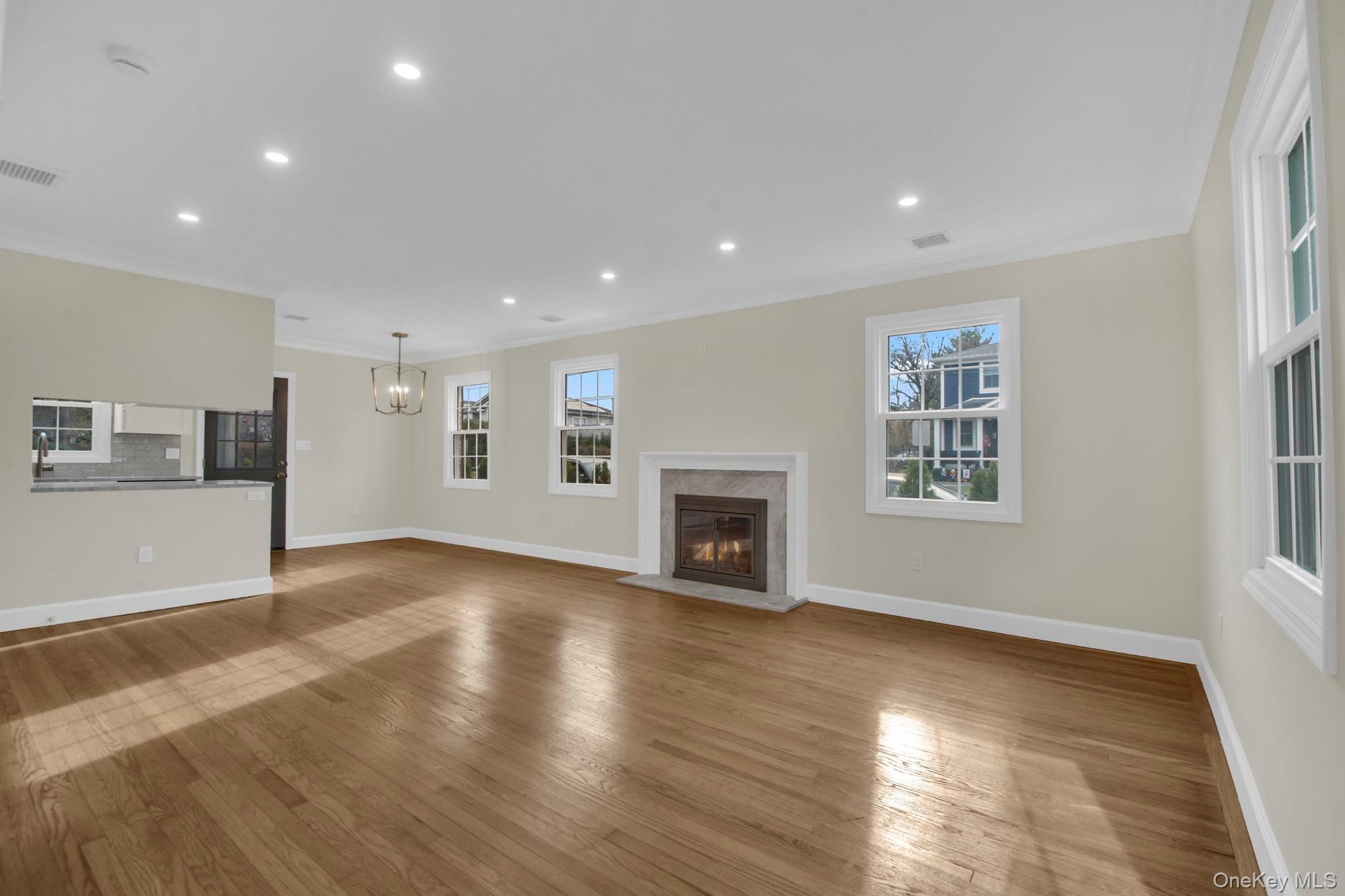 2 Bayview Court Manhasset, NY 11030 - Photo 3 of 21 Open/ Bright living room with recessed lighting, crown molding, a fireplace, light wood finished floors, and a chandelier