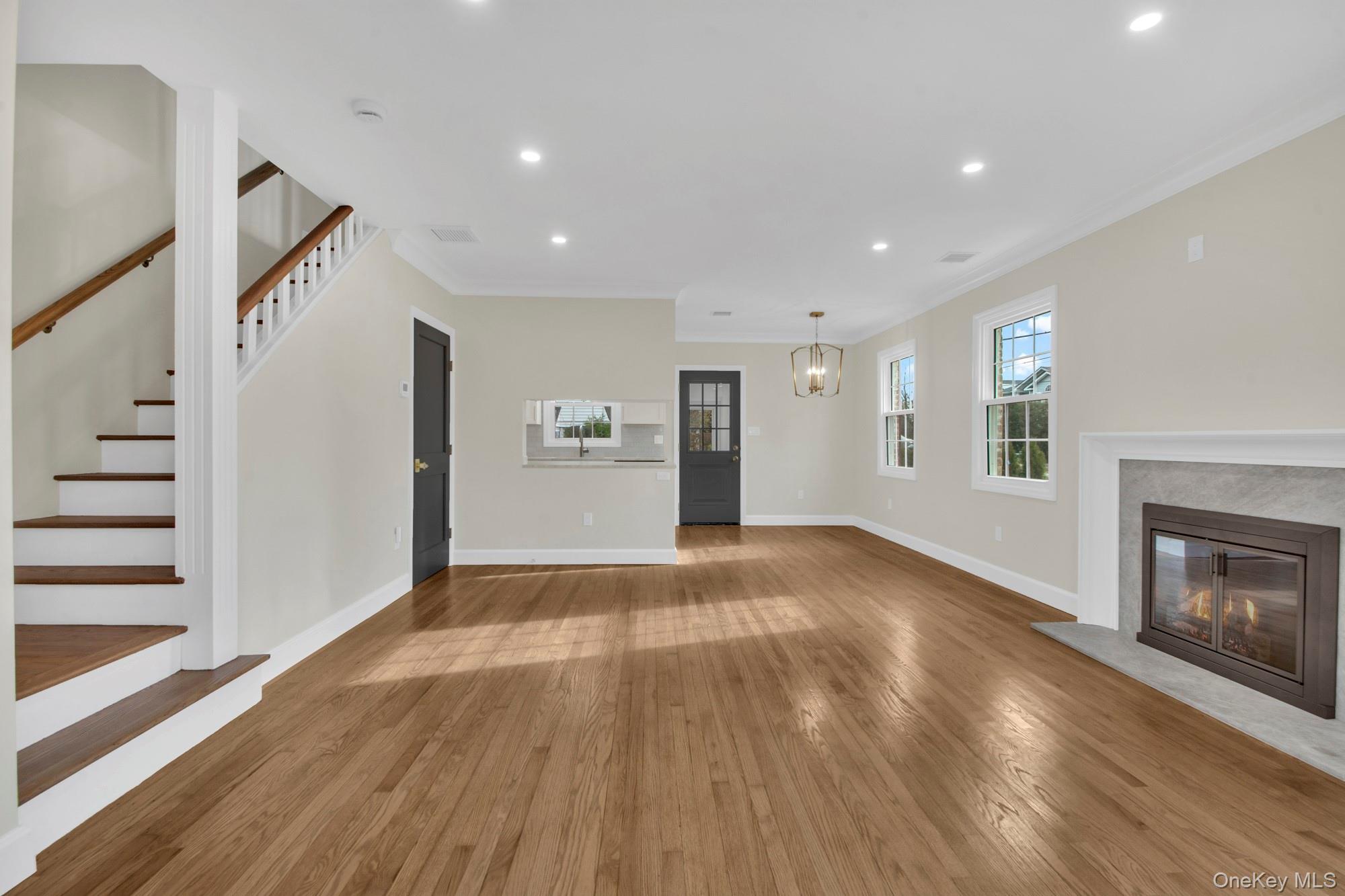 2 Bayview Court Manhasset, NY 11030 - Photo 4 of 21 Open/ Bright living room featuring recessed lighting, ornamental molding, hardwood / wood-style flooring, a premium fireplace, and stairway