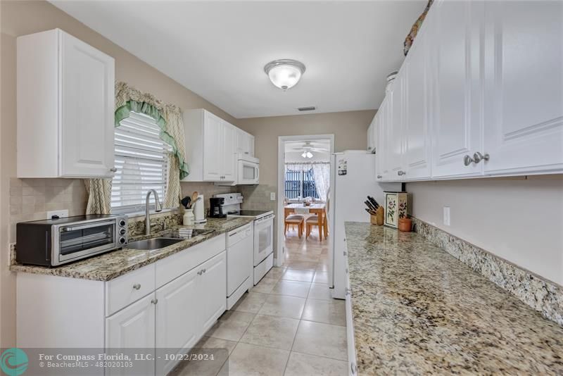 7359 Pine Park Drive North Lake Worth, FL 33467 - Photo 12 of 47 a kitchen with stainless steel appliances granite countertop a sink a stove and cabinets