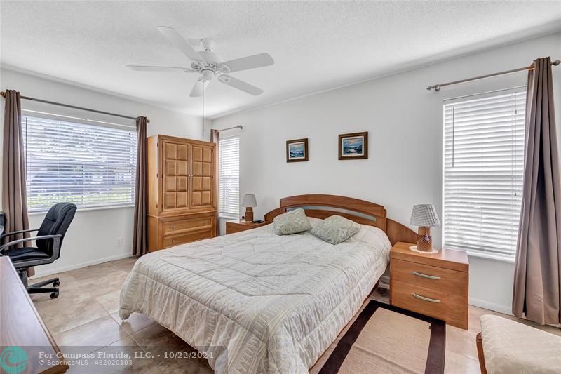 7359 Pine Park Drive North Lake Worth, FL 33467 - Photo 19 of 47 a bedroom with a bed a desk and chair with the large mirror