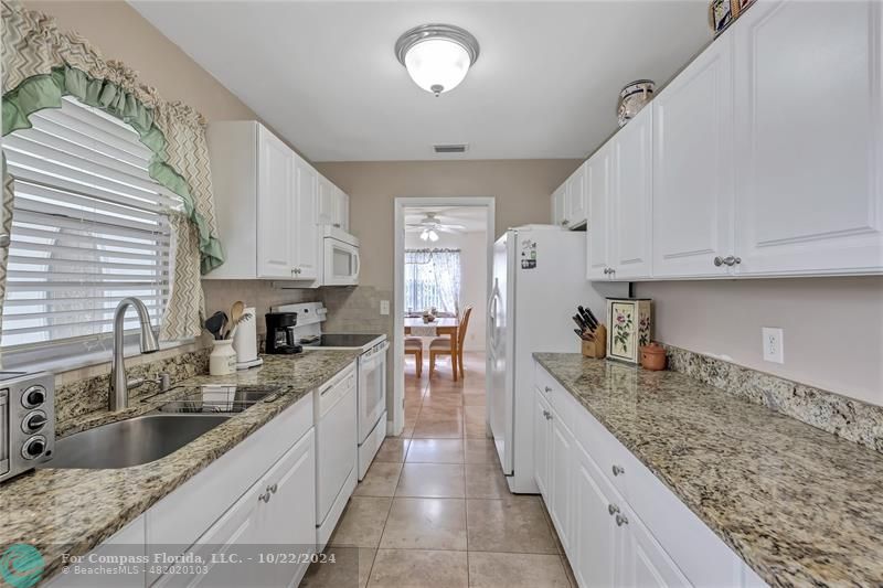 7359 Pine Park Drive North Lake Worth, FL 33467 - Photo 10 of 47 a large kitchen with granite countertop a sink a counter top space appliances and cabinets