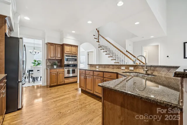 a kitchen with stainless steel appliances granite countertop a sink refrigerator and cabinets