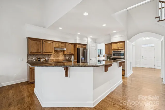 a kitchen with stainless steel appliances granite countertop a refrigerator a stove and a sink