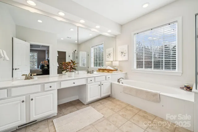 a large white bathroom with a large tub sink shower and vanity