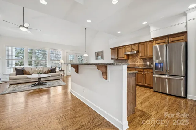 a view of kitchen with stainless steel appliances granite countertop a refrigerator and a stove top oven
