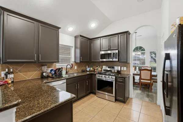a kitchen with stainless steel appliances granite countertop a sink stove and refrigerator