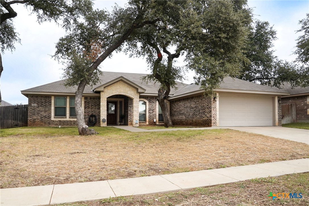 a view of a house with a yard and large tree