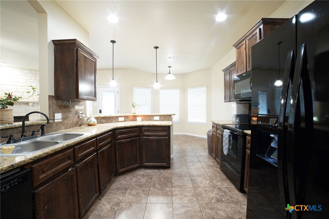 3422 Doss Street Copperas Cove, TX 76522 - Photo 11 of 29 a large kitchen with stainless steel appliances kitchen island granite countertop a sink counter space and a window