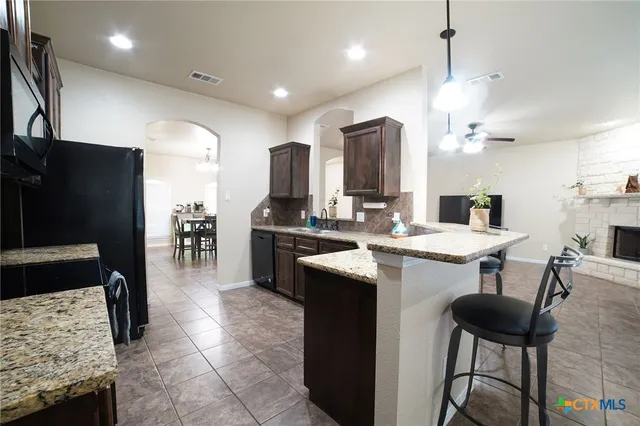 a kitchen with stainless steel appliances kitchen island granite countertop a table chairs and a refrigerator