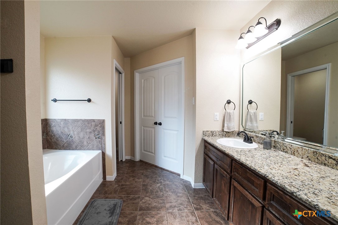 3422 Doss Street Copperas Cove, TX 76522 - Photo 16 of 29 a bathroom with a granite countertop tub sink and mirror