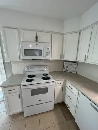 a white kitchen with stove top oven and cabinets