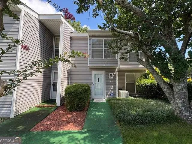 a view of a yard in front of a house with plants and large tree