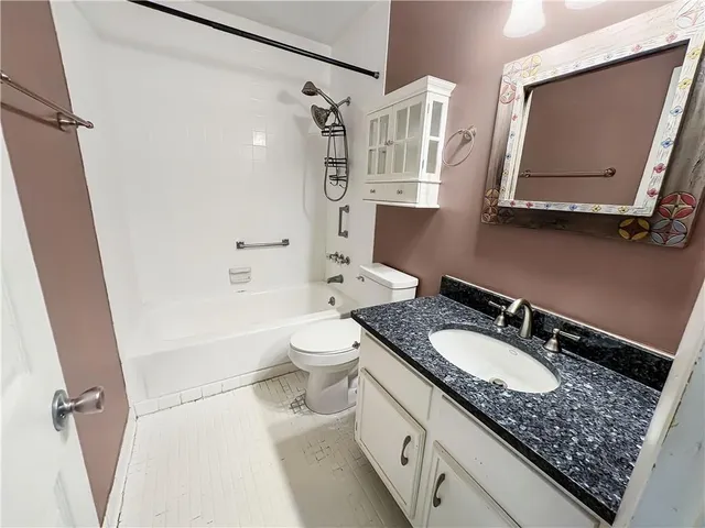 a bathroom with a granite countertop sink a mirror a bathtub and a shower
