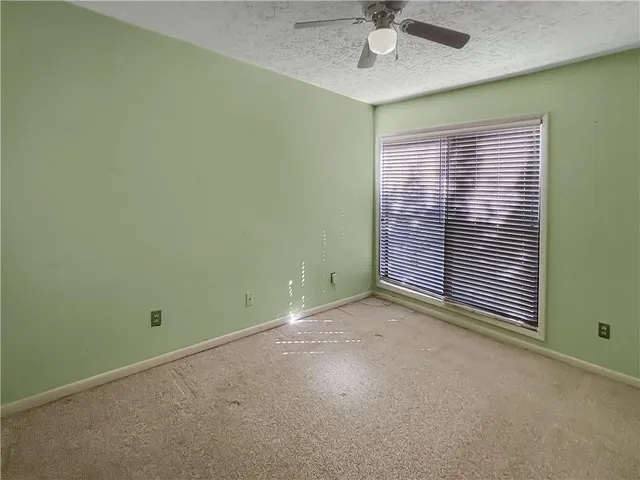 an empty room with a window and a fan