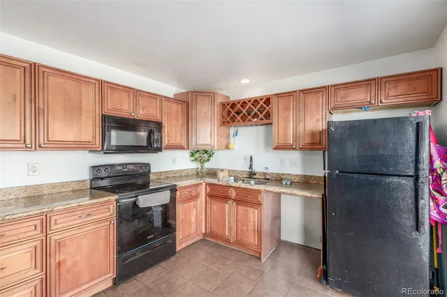 a kitchen with a sink a refrigerator and a stove top oven with wooden floor