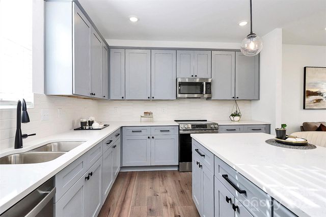 a large kitchen with kitchen island lots of counter space a sink appliances and a window