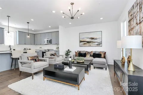 a living room with furniture kitchen view and a chandelier