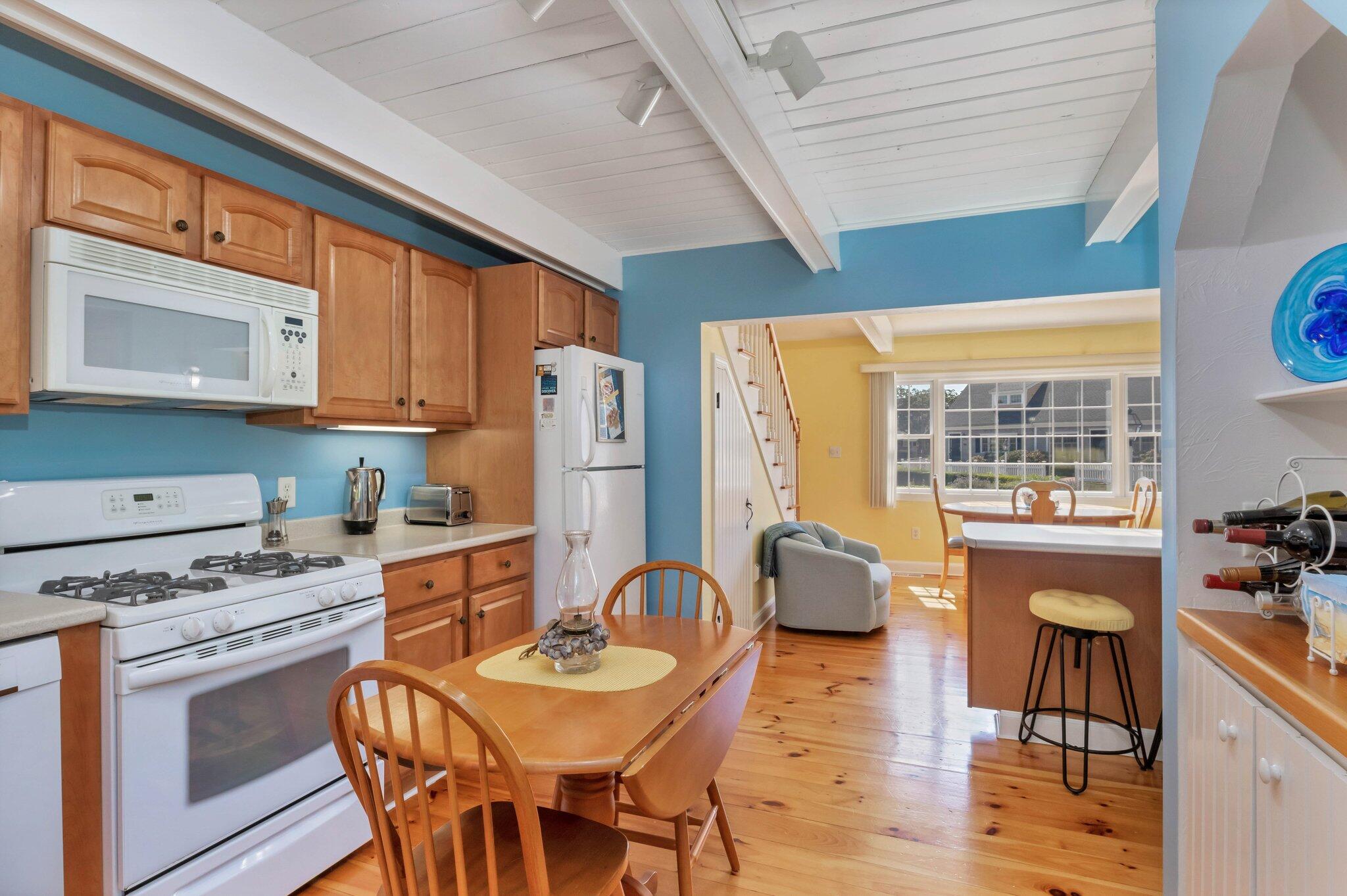 153 Jericho Path, Unit 8U Falmouth, MA 02540 - Photo 14 of 52 a kitchen with stainless steel appliances granite countertop a stove a refrigerator a kitchen island a dining table and chairs with wooden floor