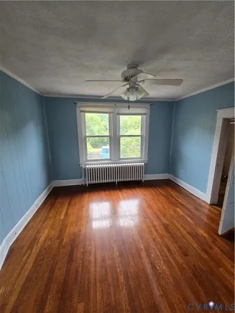 an empty room with wooden floor fan and windows