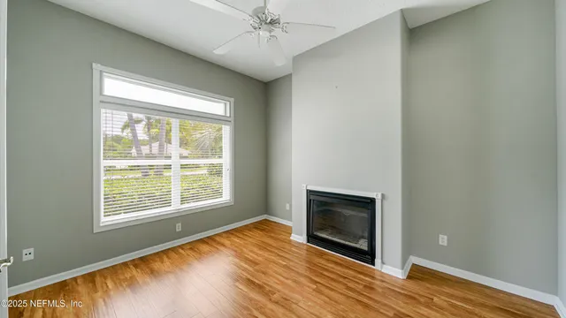 a view of an empty room with wooden floor and a window