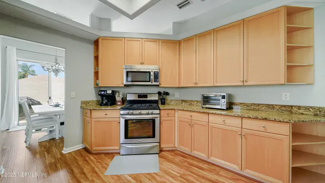 a kitchen with stainless steel appliances granite countertop a stove a sink and a microwave
