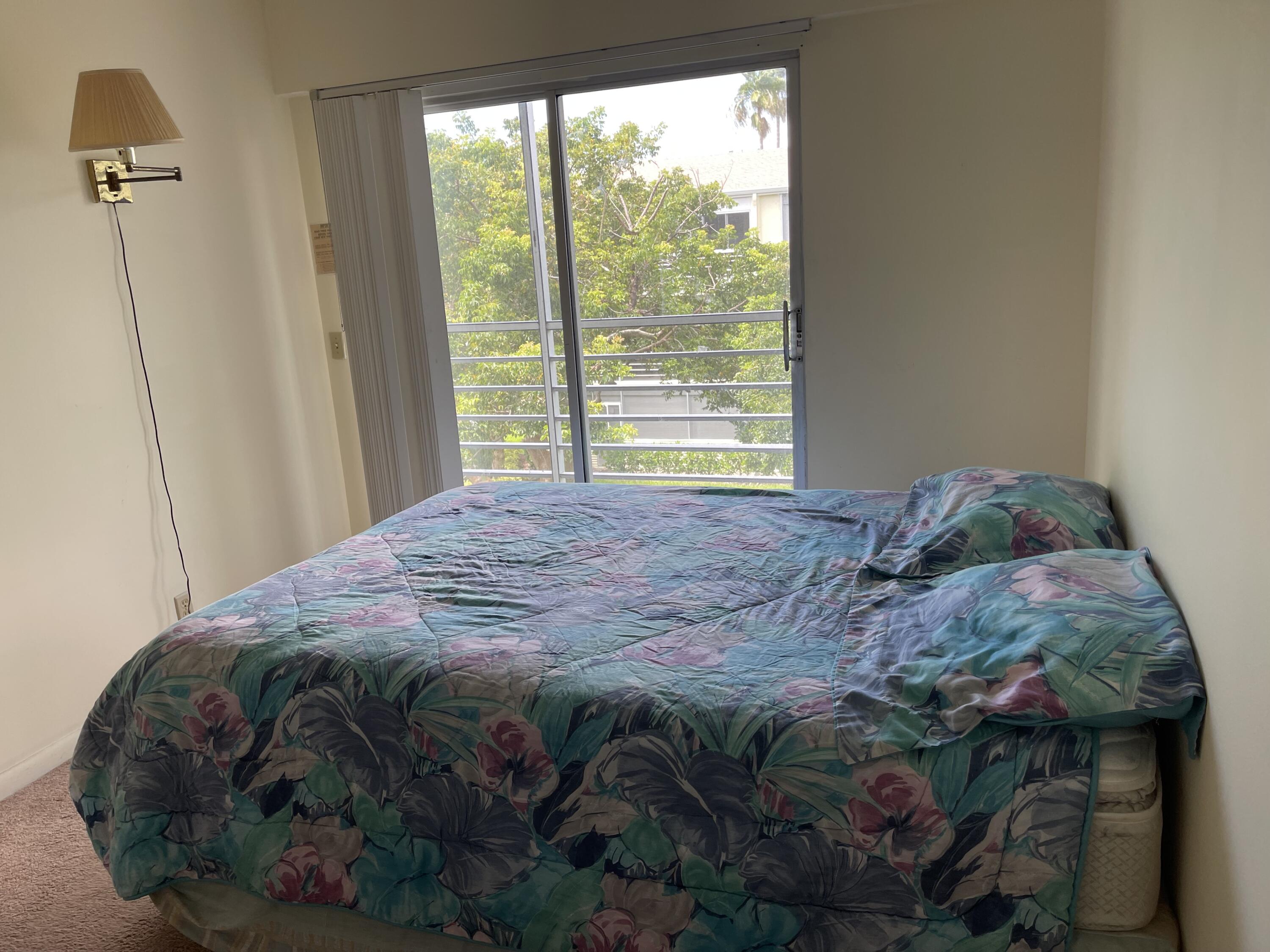 198 Dorset East, Unit E Boca Raton, FL 33434 - Photo 15 of 23 a bed sitting in a bedroom next to a window