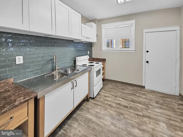 a kitchen with granite countertop a sink stove and cabinets