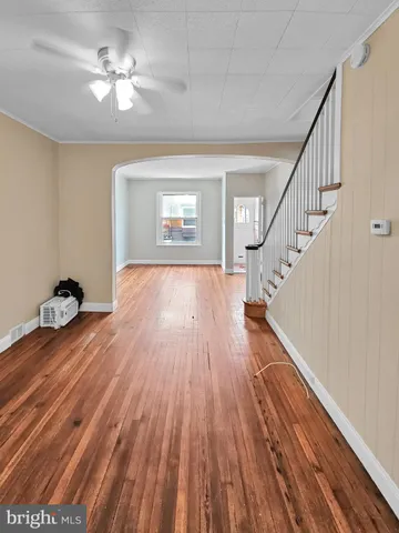 a view of empty room with wooden floor and fan