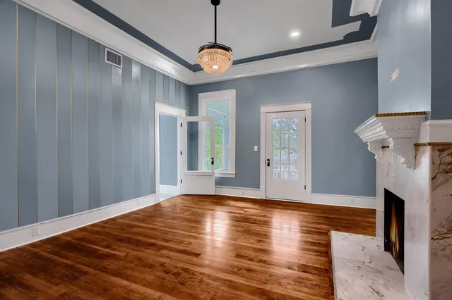 a view of a livingroom with a fireplace a chandelier and wooden floor