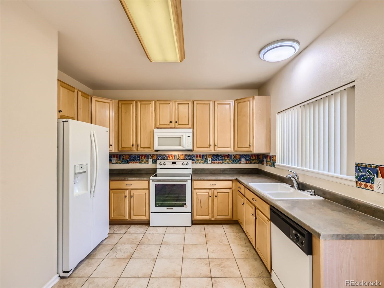 422 Chambers Way Aurora, CO 80011 - Photo 14 of 44 a kitchen with a sink a refrigerator and cabinets