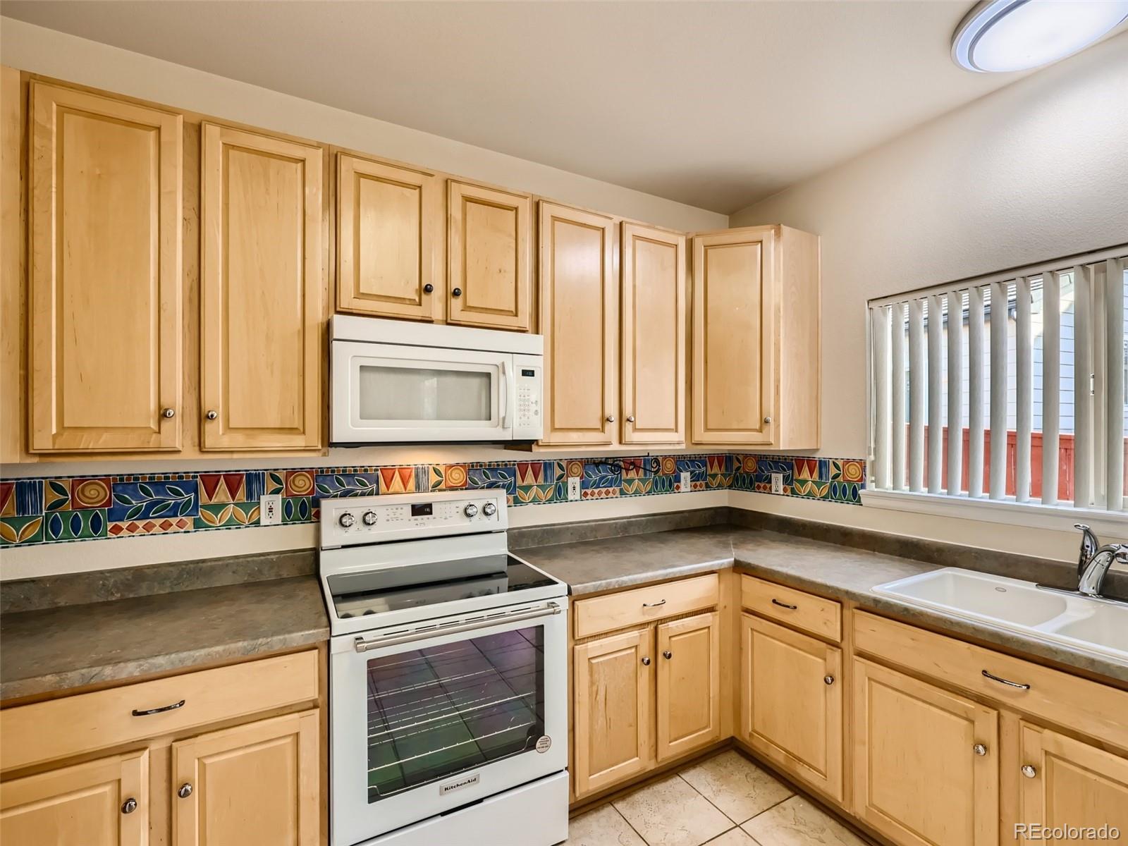 422 Chambers Way Aurora, CO 80011 - Photo 15 of 44 a kitchen with stainless steel appliances a sink a stove and white cabinets