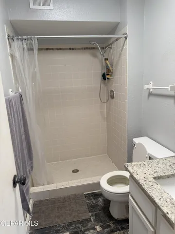 a bathroom with a granite countertop bathtub shower sink and toilet