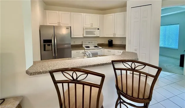 a kitchen with stainless steel appliances granite countertop a refrigerator a stove a sink and a dining table