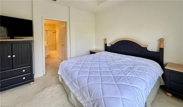 a bedroom with a bed and a flat tv screen on dresser