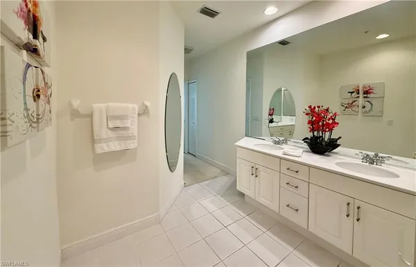 a spacious bathroom with a double vanity sink a large mirror a shower and vanity