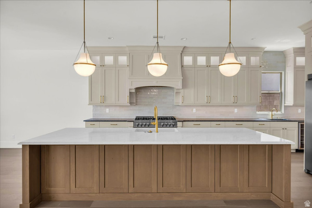1620 Belayer Drive St. George, UT 84770 - Photo 14 of 51 Kitchen featuring a large central island with a light-toned countertop, a gold-toned faucet, and three contemporary pendant lights