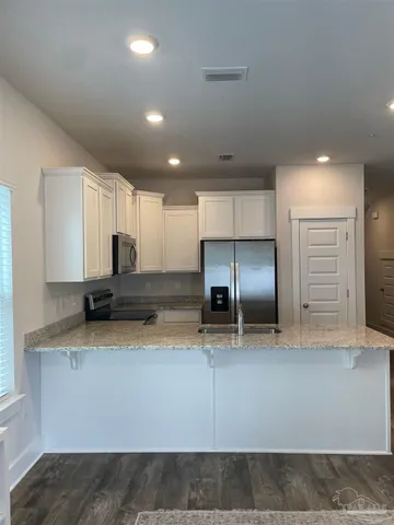 a kitchen with stainless steel appliances granite countertop a sink a stove and a refrigerator