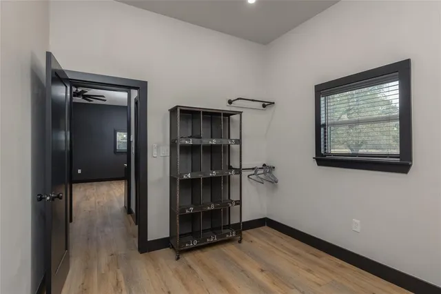 a view of an empty room with wooden floor and a ceiling fan