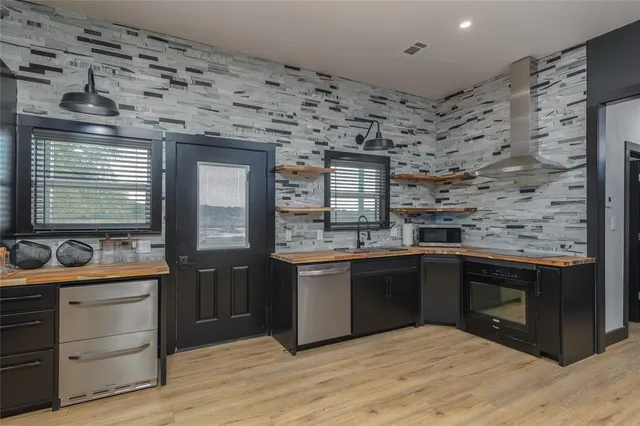 a large kitchen with stainless steel appliances granite countertop a refrigerator a sink a stove and a wooden floors