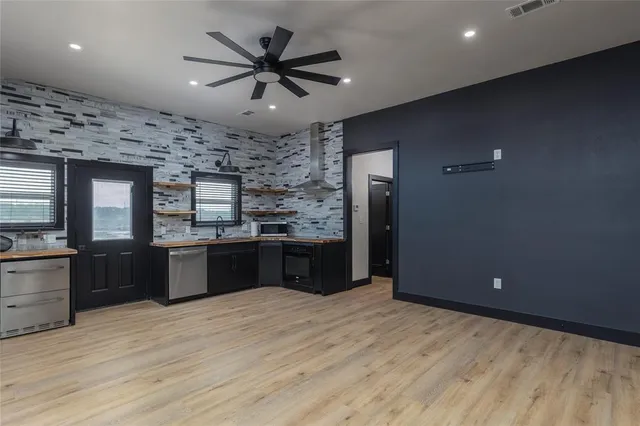 a large kitchen with stainless steel appliances granite countertop a refrigerator a sink dishwasher a stove and white countertops with wooden floor