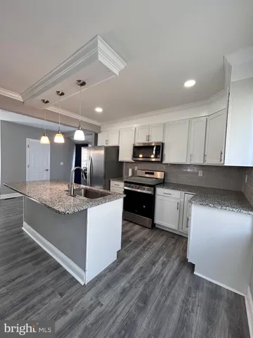 a kitchen with stainless steel appliances kitchen island granite countertop a stove a sink and a refrigerator