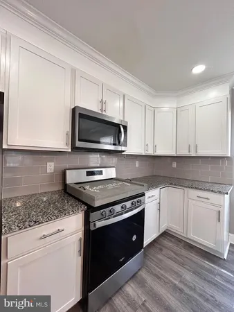 a kitchen with granite countertop cabinets stainless steel appliances and a wooden floor