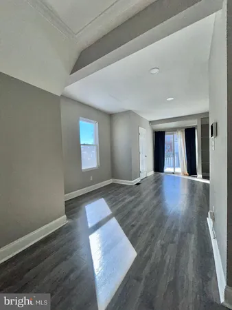 a view of an empty room with window and wooden floor