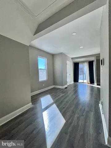 a view of an empty room with window and wooden floor