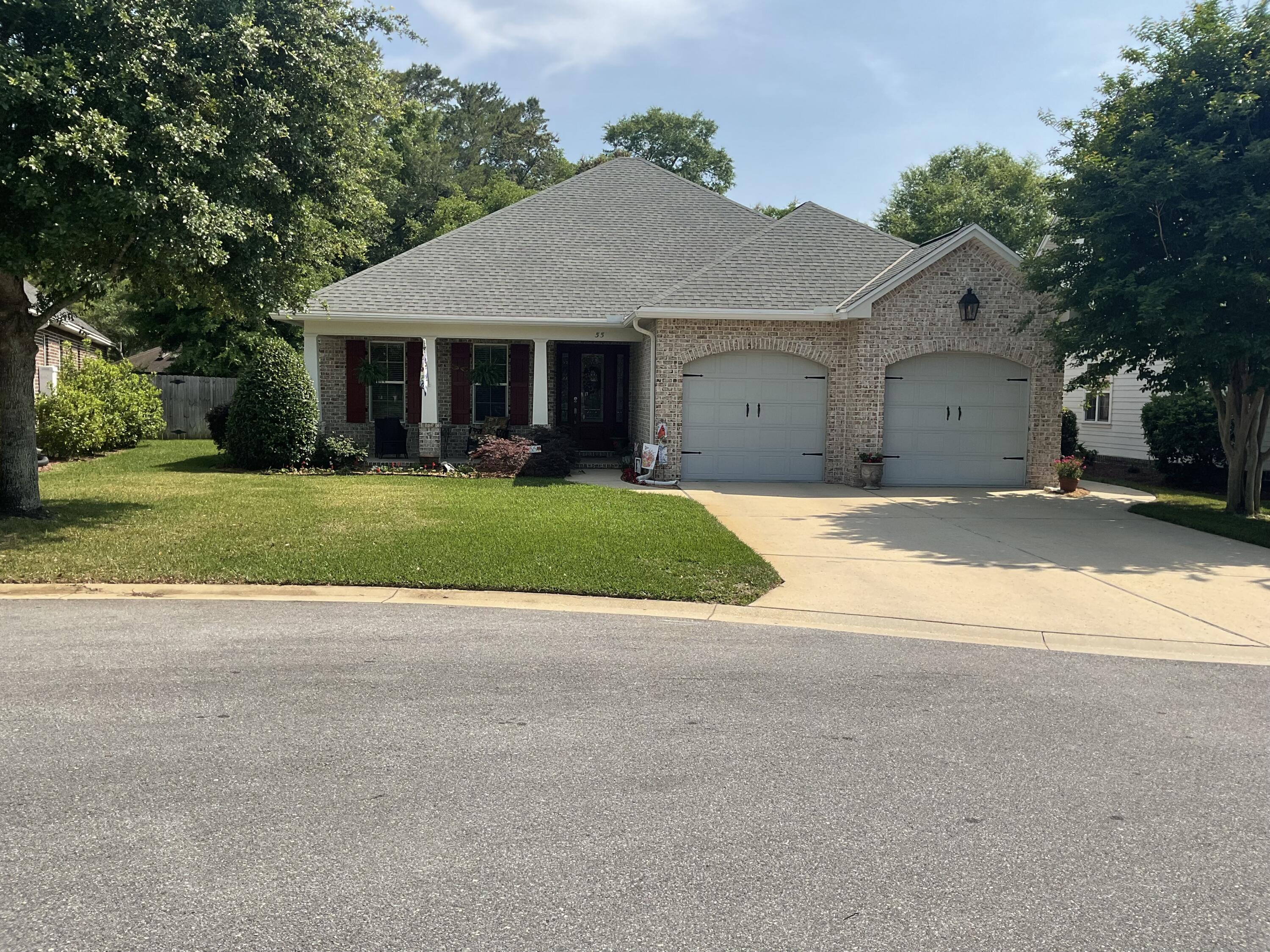 a view of a house with a yard and large tree