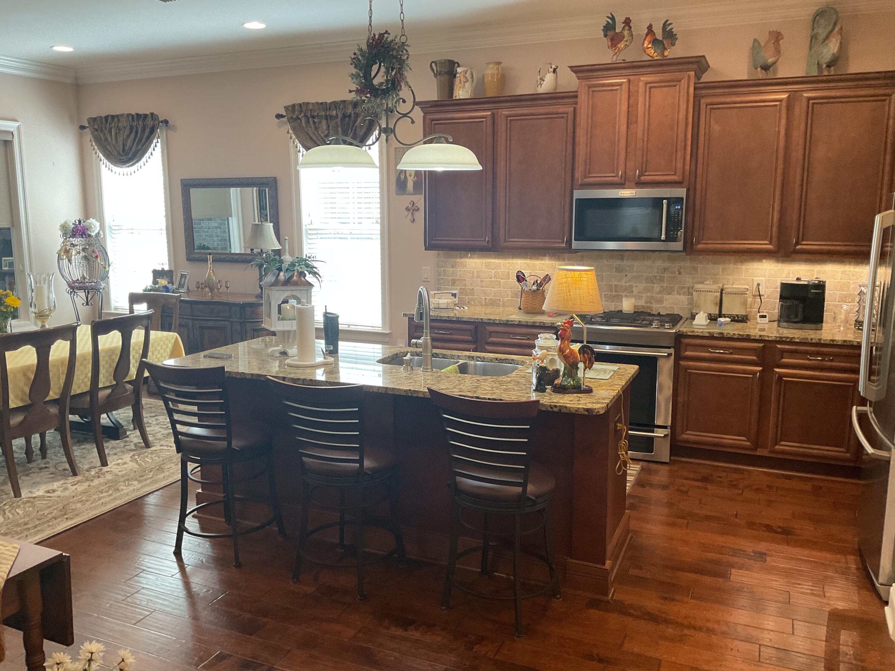 55 Derby Downs Circle Niceville, FL 32578 - Photo 19 of 34 a kitchen with stainless steel appliances granite countertop a stove a sink dishwasher a dining table and chairs with wooden floor