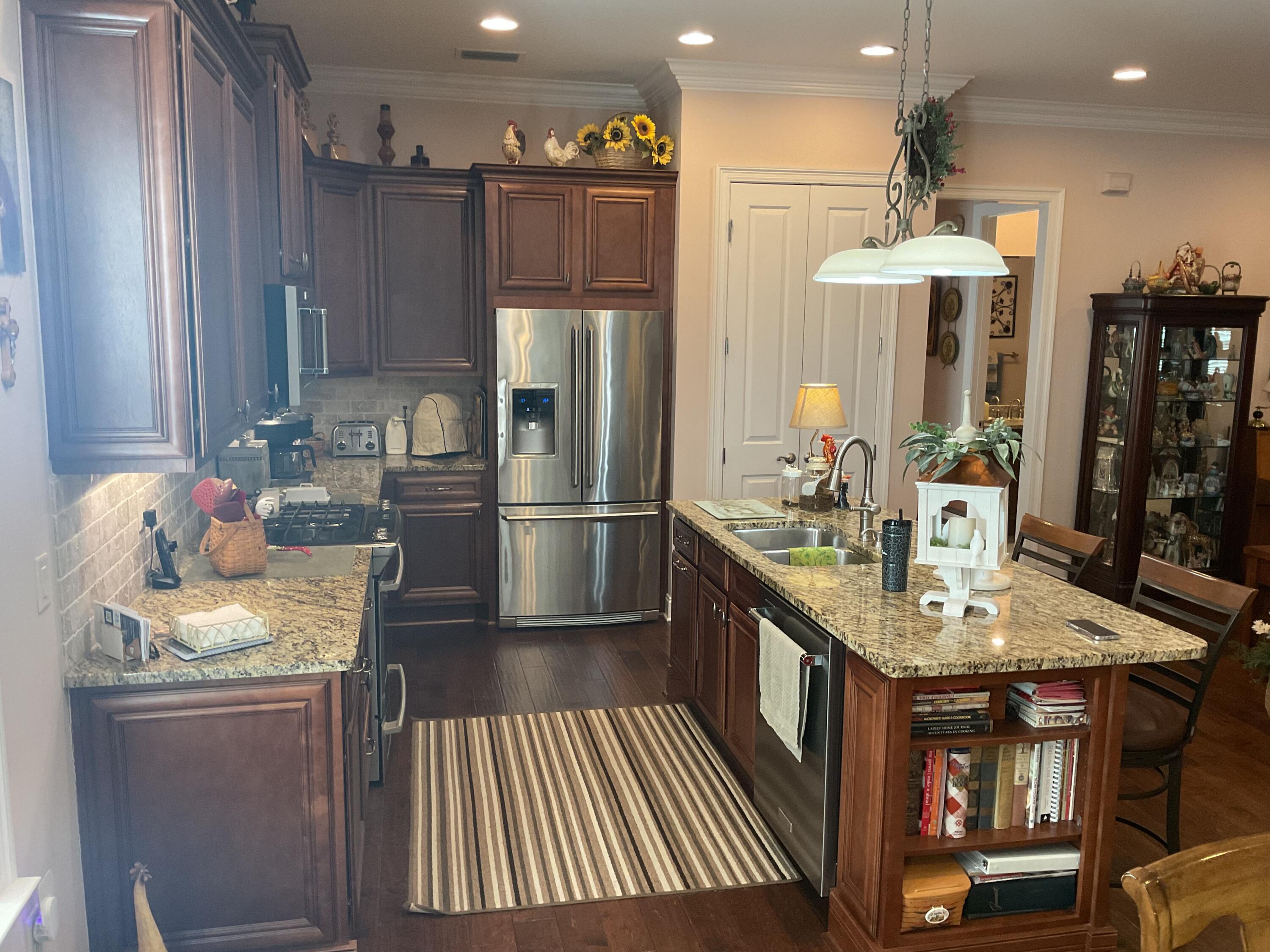55 Derby Downs Circle Niceville, FL 32578 - Photo 20 of 34 a kitchen with stainless steel appliances granite countertop a refrigerator a sink dishwasher a stove and a dining table with wooden floor