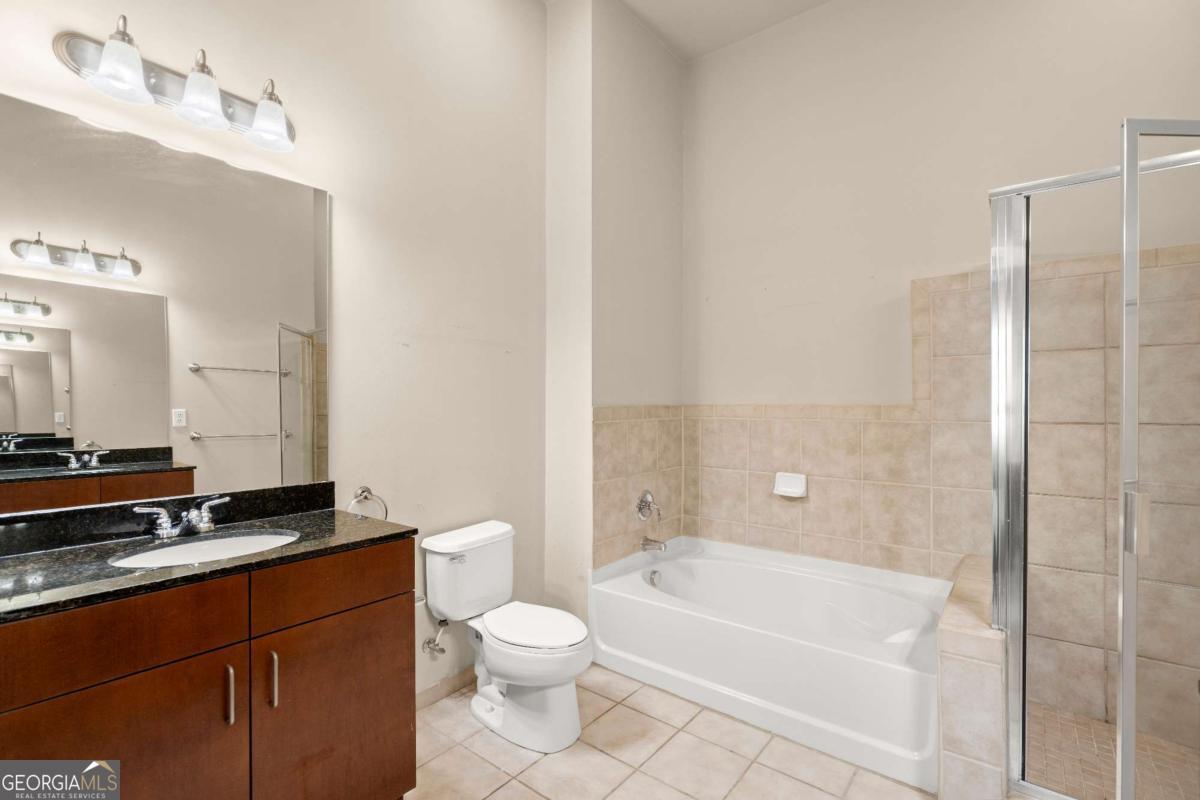711 Cosmopolitan Drive Northeast, Unit 442 Atlanta, GA 30324 - Photo 12 of 32 a bathroom with a granite countertop sink a toilet and bathtub