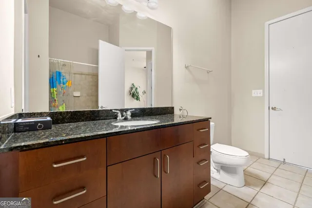 a bathroom with a granite countertop sink a toilet and a mirror