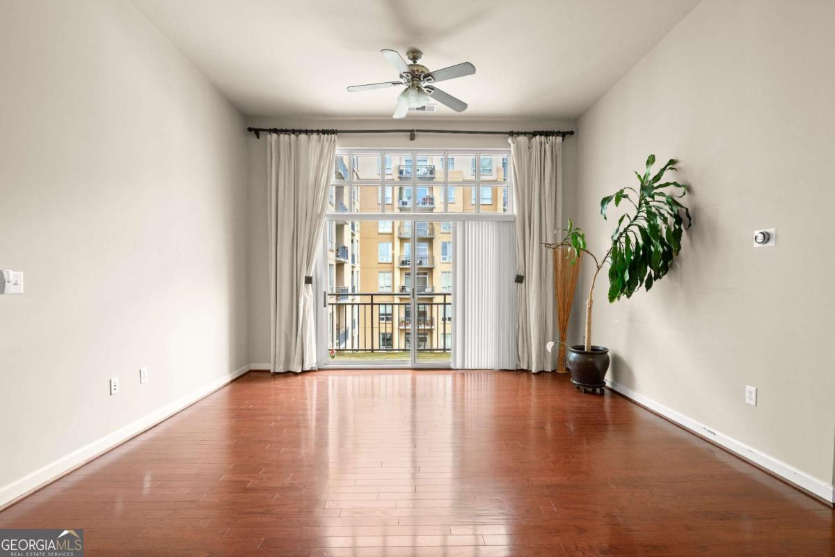 711 Cosmopolitan Drive Northeast, Unit 442 Atlanta, GA 30324 - Photo 3 of 32 a view of an empty room with a window and wooden floor